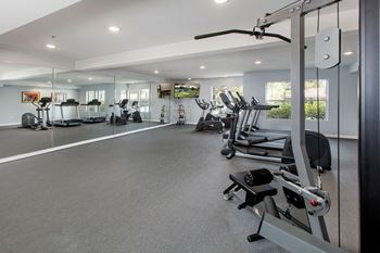 A spacious gym with a variety of equipment including treadmills, elliptical machines, and weight machines.